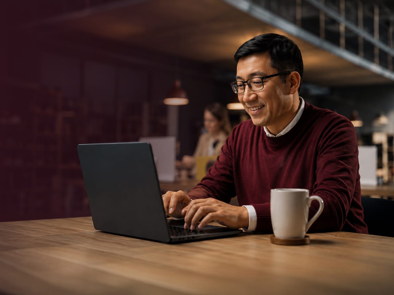 A man working on a laptop at a shared table in a co-working space