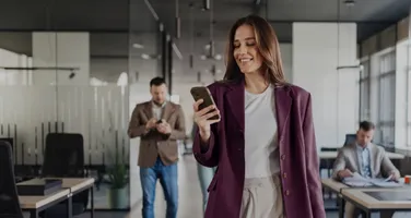A woman walking through an office while checking her phone