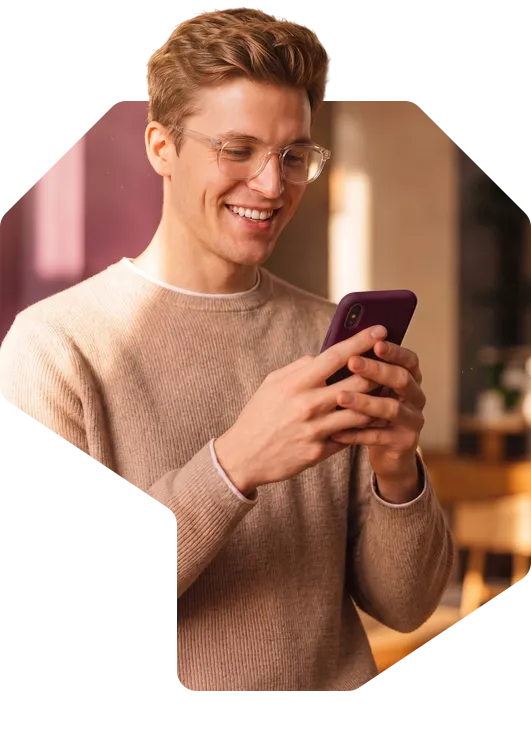 A smiling young man in glasses looking at his phone