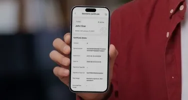A phone showing a verification result, held up by a person in a red shirt